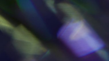 Parlak yansıma. Bulanık gökkuşağı lensi. Odaklanamayan sarı mor çok renkli desen, soyut sanatın koyu siyah arka planında parıldıyor..