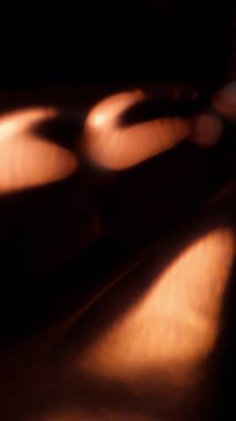 Dikey video. Soyut ışın. Odaklanamayan parıltı. Parıldayan ışıldayan görkemli mercek altın sarısı parlayan parıltılar sanatın karanlık arka planında parıldıyor..