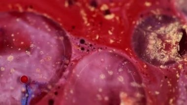 Boya damlası. Işıldayan sıvı. Parlak soyut bulanık parçacıkların arka planında hareket eden parlak kırmızı renkli mürekkep sıvısı..