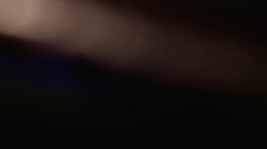 Şafak. Bulanık parıltı. Siyah sanat arka planında sönük mavi yeşil çok renkli gökkuşağı tayfı yanıp sönüyor..