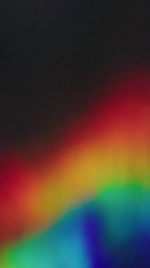 Dikey video. Gökkuşağı merceği parlıyor. Bulanık ışın titreşimi. Odaklanamayan sızıntı, çok renkli, yeşil, parlak ışınlar, koyu siyah, soyut, aydınlık sanat arkaplanı..