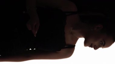 Dikey video. Tasasız siluet. Olumlu neşe. Siyah üzerinde dans etmekten hoşlanan esinlenilmiş bir kadının koyu renk kontrast şekli..