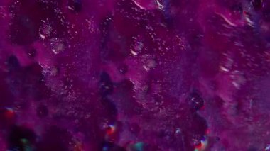 Neon sıvısı damlası. Odaklanamayan parıltı. Boya akışı parçacığı mor renkli parlak sıvı soyut koyu bokeh ışığı üzerine.