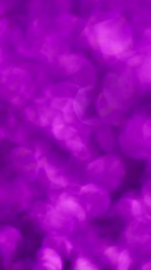 Dikey video. Bulanık ışık. Mor konfeti. Işıltılı noktaların pürüzsüz geçiş noktalarıyla parıldayan yuvarlak noktalar. Garip yanardöner parıltı..