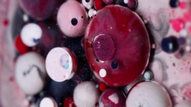 Dikey video. Renkli boya. Kabarcık emülsiyonu. Kırmızı gri beyaz akrilik küreler, sanatın soyut arka planında şeffaf su boyası püskürtme karışımı..