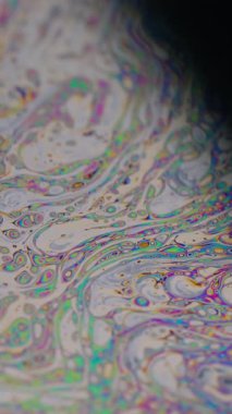 Dikey video. Boya karışımı. Benzin var. Odaklanamayan mor yeşil sıvı yağ eğrisi koyu siyah, bulanık ışık, soyut sanat arka planında akrilik kaygan.