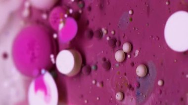 Dikey video. Boya akışı. Kabarcık emülsiyonu. Canlı pembe beyaz su karışımı yüzen renkli damlalar patlama dokusu. Dalgalar soyut arkaplanı doldurur.