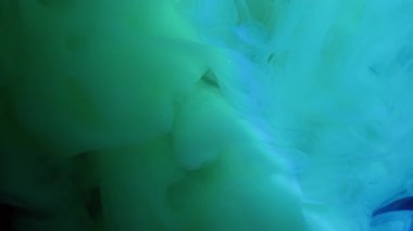 Mürekkep buharı. Puf boyası. Işıldayan suda yeşil mavi turkuaz girdap bulutu akıyor. Gizemli odaksız peçe sanatı soyut neon akış arkaplanı.