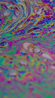 Dikey video. Holografik küre. Baloncuk yağı. Odaklanmamış mor yeşil sıvı boya eğrisi koyu siyah bulanık ışık soyut sanat arka planında akrilik kaygan.