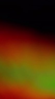 Dikey video. Bulanık arka plan. Holografik etki. Odaksız sızıntı. Çok renkli yeşil ışınlar. Gökkuşağı, soyut sanat ışığı üzerinde parlak bir ışık yansıması oluşturur..