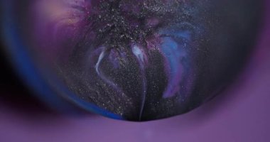 Odaklanamayan parlak emülsiyon. Prizma sıvısı. Küre merceğinin soyut arka planında siyah parıldayan sıvı sızıntısı var. Mor mavi boya kozmik renk karışımı.