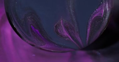 Parıltı akıyor. Bulanık akrilik akıntı. Küre lensinde siyah mor, köpüklü su karışımı mürekkep pigmenti. Odaklanmamış koyu renk arkaplanı.