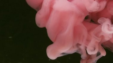Mürekkep buharı. Atmosferik duman. Odaklanamayan pembe renkli su akışı kimyasal sıçrama fantazisi soyut koyu siyah arkaplan üzerinde hareket ediyor.
