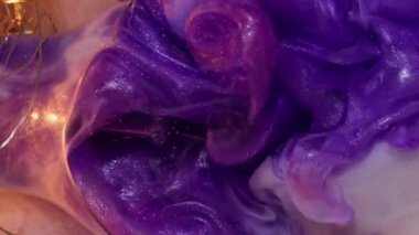 Dikey video. Mürekkep dumanı. Sanat bulanıklığı. Siyah arka planda altın parıltılı duvak karışımı. Kırık ampul parçaları. Renkli suyla aydınlatılmış çelenk..