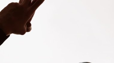 Dikey video. Karantina sohbeti. Uzaktan iletişim. Beyaz boş arkaplanda izole edilmiş telefon mesajı kullanarak yüz maskeli bir adamın karanlık profil silueti.