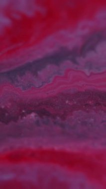 Dikey video. Odaklanmamış dökülme. Sıvı mermer dokusu. Çok renkli, parlak kırmızı boya akışı soyut, bulanık bokeh ışık sanat arka planında hareket eden parlak parçacıklar..