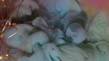 Dikey video. Çok renkli duman. Boya karışımı. Dalgalı sıvı sis mürekkebi kırık cam parçalarını yıkıyor. Işıldayan pembe gri mavi soyut arkaplan sanat suyu.