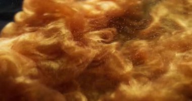 Parıltılı boya. Toz sıvısı. Altın parçacıklar suya parlak pigmentler saçar. Parlak soyut bulanık bulut patlaması siyah arkaplan.