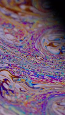 Dikey video. Psikedelik akış. Sıvı çok renkli. Odaklanmamış mor turuncu, mavi, turuncu, sıvı yağ eğrisi koyu siyah, bulanık ışık, soyut sanat arka planında akrilik kaygan..