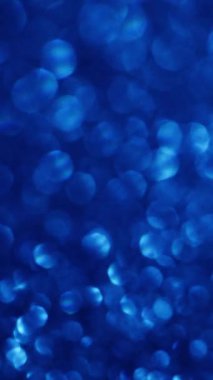 Dikey video. Bulanık mavi. Parıltılı bir parlama. Renk değişimi ile dekoratif şenlik arka planı. Kaotik ışınları titretiyor. Hassas fantezi atmosferi..