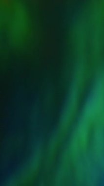 Dikey video. Bulanık kırılma ışığı. İşaret fişeği etkisi. Odaklanamayan sızıntı, çok renkli yeşil ışınlar gökkuşağı, soyut sanat arkaplanındaki gradyan ışın lenslerini titretiyor..