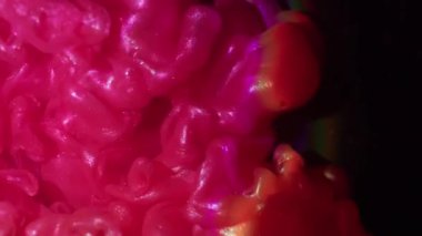 Parlayan toz. Boya patlaması. Parlak dumanlı pembe turuncu parlak dalga siyah arka planda. Sanat sıvısı tozu soyut bulanık doku.