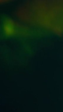 Dikey video. Soyut bulanıklık. İşaret fişeği. Işıldayan sarı turuncu mavi çok renkli parlak yanıp sönen ışıklar karanlık sanat arka planında hareket ediyor..