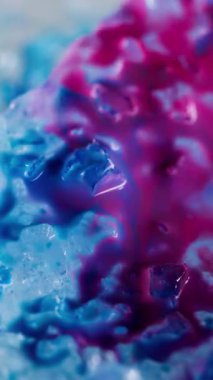 Dikey video. Mürekkep damlası. Soyut boya. Mavi pembe renk buz karışımı akışı. Sıvı karışımı. Bulanık sanat dokusuna dökülen sıçrama..