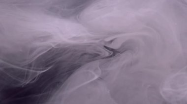 Duman bombası. Buhar bulutu. Odaklanmamış mor renkli sisli doku su patlaması akışında mürekkep sıçratır soyut sanat kara arka planda yüzer.