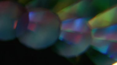 Parlak ışık. Bulanık yuvarlak işaret fişeği. Odaklanamayan neon ışıklı gözlük mercek dokusu soyut koyu siyah arkaplanda titreşiyor.