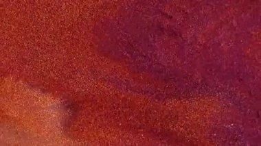 Parlayan toz. Akrilik dökülmesi. Renkli boya cilası ıslak doku akış gölgesi. Parlak mor turuncu sanat tozu soyut arkaplanı bulanıklaştırır.