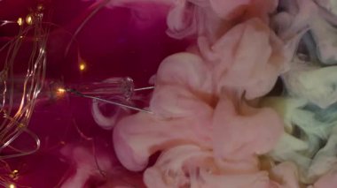 Dikey video. Yaratıcı duman. Boya dumanı. Pembe köpüklü suda peçe mürekkebi dalgalanması. Kırık parlak ampul dekoratif soyut arkaplan.