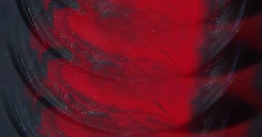 Parlak mürekkep akışı. Parlak bulanık karışım. Yuvarlak merceğe renk simleri dökülüyor. Siyah sıvı bulanık arkaplanda çözünen kırmızı boya.