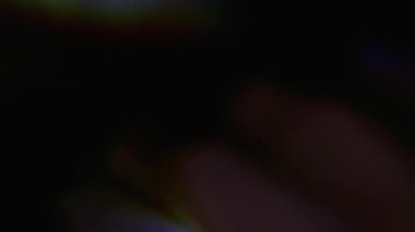 Işıl ışıl. Bulanık ışık. Odaklanmamış mavi yeşil renkli ışık spektrumu soyut koyu siyah arkaplanda hareket ediyor.