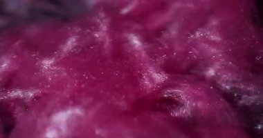 Shimmering liquid. Ink wave. Purple pink sand metallic powder smoke blend water. Shiny flow splash spread color abstract black background.