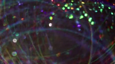 Disko parıltısı. Odaklanamayan şenlik titreşimleri. Bulanık bokeh ışık arkaplanı üzerinde hareket eden ışıl ışıl parlayan çok renkli parçacıklar..
