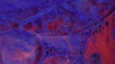 Işıldayan boya. Odaklanamayan kozmetik titreşimler. Mavi kırmızı köpüklü su bulanık bokeh ışık arkaplanı üzerinde hareket ediyor.