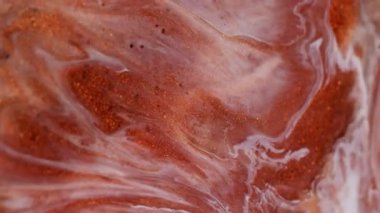 Leke sızıntısı. Parlak mürekkep. Odaklanmamış renkli parlak toz cilası parçacıkları soyut arkaplanı harmanlıyor. Turuncu kırmızı beyaz sıvı pigment dökülüyor.