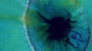 Dikey video. Parıltı patlaması. Boya dökülmüş. Sanat pigmenti ışıl ışıl ortası büyük mavi turkuaz akıntısı. Renkli akış soyut arkaplan.