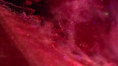 Dikey video. Parlak boya dalgası. Odaklanmış emülsiyon. Parlak turuncu kırmızı pul parçacıkları su kademeli soyut sanat arkaplanı.