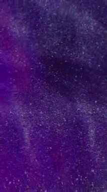 Dikey video. Bulanık toz parçacıkları. Işıltılı akış. Beyaz ışıl ışıl şeffaf toz, parlak su sıçratır soyut bokeh açık mor çok renkli arka planda hareket eder.