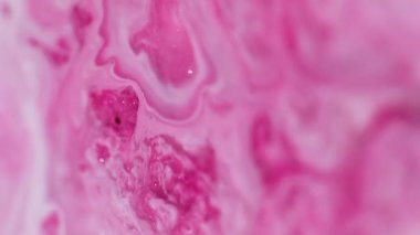 Bokeh pigment akışı. Parlak bir geçmişi var. Odaklanmamış pembe beyaz renkli boyalı su desenli mermer diş minesi sıvısı soyut sanatta ilerliyor.
