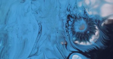 Mürekkep sıçraması. Damlama dokusu. Odaklanamayan mavi beyaz renkli su kimyasalı soyut arka planda siyah lekeler yayılıyor..