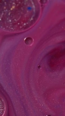 Dikey video. Mürekkep akışı. Nehir boyası. Pembe tonda. Yağlı altın parıltılı baloncuk. Yumuşak renk arkaplan karışımı. Emülsiyon parlama etkisi.