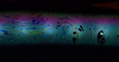 Renkli sıvı. Girdap sabunu. Spektrum yağlı sıvı fantezi gökkuşağı mürekkebi suyu çözdü. Soyut siyah arkaplanda mor yakıt boyası karışımı.