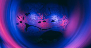 Mürekkep karışımı. Neon akışı. Bokeh yuvarlak lens efekti renkli tünel pervazı. Siyah arkaplanda mavi pembe küre ışık yansıması.