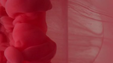 Dikey video. Boya damlası. Mürekkep kabarcığı. Odaklanmamış kırmızı renk buhar bulutu dokusu sıvısı ışık soyut sanat arka planında cam küre üzerine sıçrıyor.