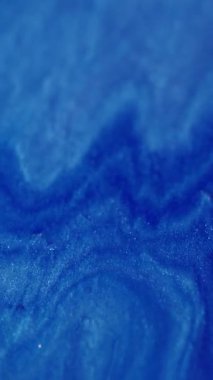 Dikey video. Görüntü parıldayan sıvı. Işıl ışıl. Renkli mavi, yanıp sönen sıvı boya mürekkebi soyut bokeh ışık arkaplanı üzerinde hareket eden parlak toz..