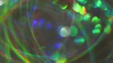 Bulanık sanat pırıltısı. Dönen ışık. Yeşil mavi turuncu çizgiler, çok renkli yanıp sönen mercekler, kaleydoskop şenliği soyut arka planında parıldıyor..