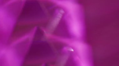 Kaleydoskop üçgenleri. Odaklanmamış parlaklık. Sarı yeşil, mor, parlak, parlak desenli mercek fişeği soyut, aydınlık arka planda hareket ediyor..